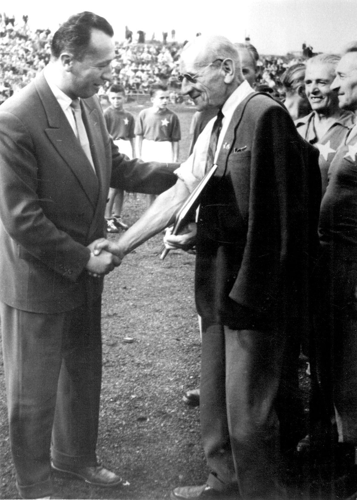 Prezes Wisły S. Żmudziński składa podziękowanie za sukcesy poprzednich pokoleń piłkarskich na ręce najsłynniejszego piłkarza w dziejach Towarzystwa, Henryka Reymana (17 sierpnia 1958 r.). Źródło: historiawisly.pl